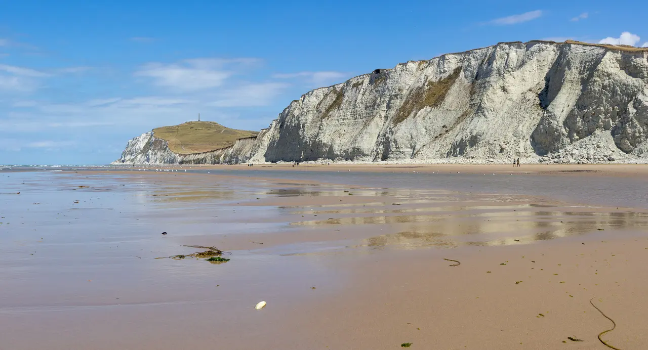 The chalk cliffs of Cap Blanc-Nez on the French coast near Calais, seen across a wide sandy beach at low tide